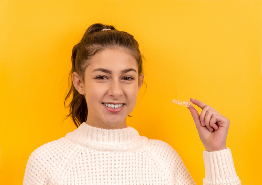 a person in a sweater holding a dental retainer